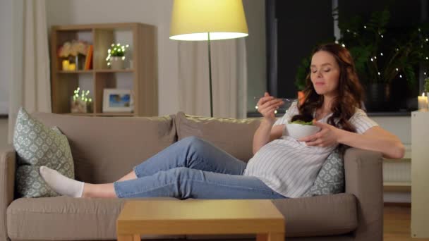 Glad leende gravid kvinna äter sallad hemma — Stockvideo