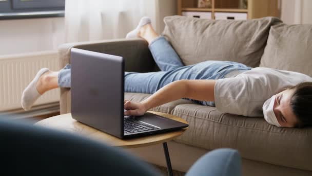 Mujer aburrida enferma con el ordenador portátil acostado en el sofá en casa — Vídeo de stock