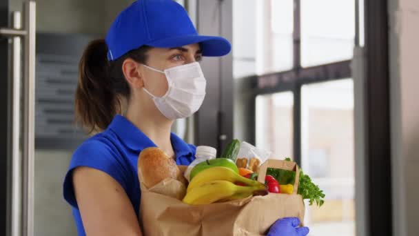 Entrega mujer en mascarilla con comida en bolsa de papel — Vídeos de Stock