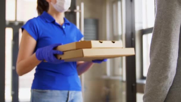 Доставка девушка в маске давая пиццу коробки женщине — стоковое видео
