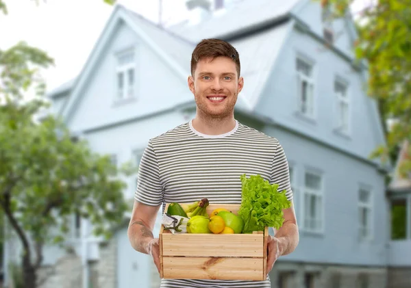 Leende man med mat i trälåda över huset — Stockfoto