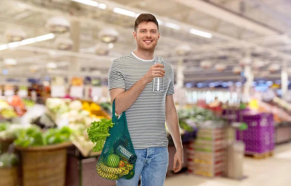 Hombre con comida en bolsa y agua en botella de vidrio — Foto de Stock