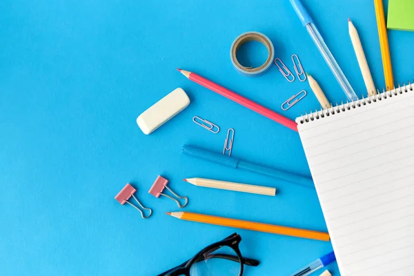 Ноутбук и школьные принадлежности на синем фоне — стоковое фото