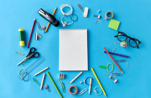 Ноутбук и школьные принадлежности на синем фоне — стоковое фото