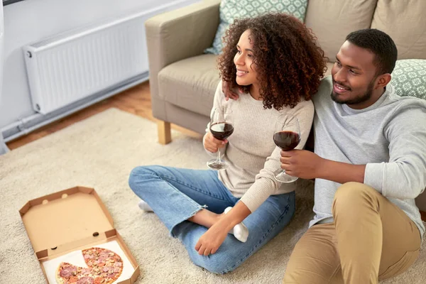 Lyckligt par med vin och takeaway pizza hemma — Stockfoto