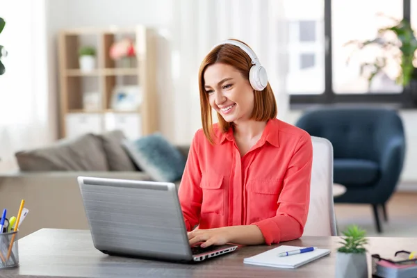 Frau mit Kopfhörer und Laptop arbeitet zu Hause — Stockfoto