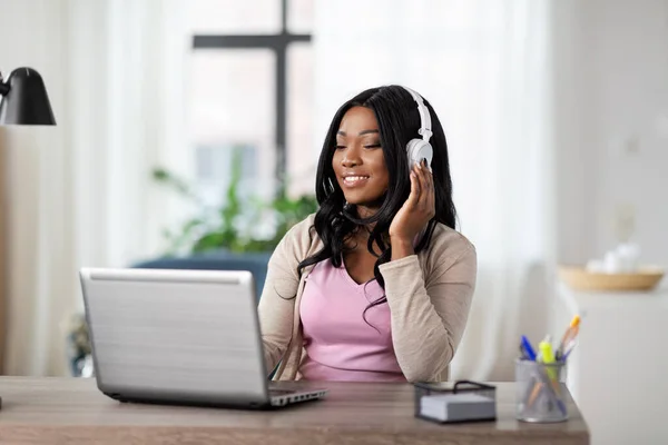 Mujer en auriculares con portátil trabajando en casa — Foto de Stock