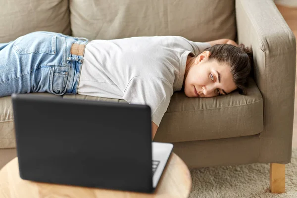 Znudzona kobieta z laptopem leżącym na kanapie w domu — Zdjęcie stockowe