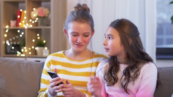 Meninas felizes com smartphone e fones de ouvido em casa — Vídeo de Stock