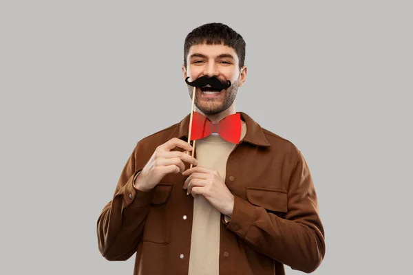 Uśmiechnięty mężczyzna z wąsami i muszką party rekwizyty — Zdjęcie stockowe