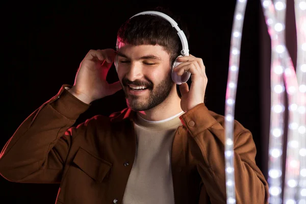 Man in headphones over neon lights of night club — Stock Photo, Image