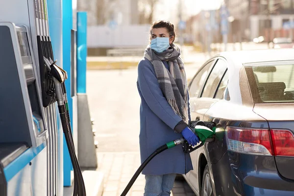 Vrouw in masker vullen van haar auto bij tankstation — Stockfoto