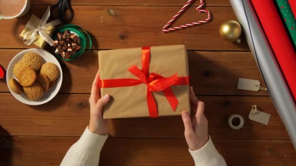 Händer med inslagen julklapp på träbord — Stockvideo