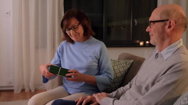 Šťastný starší pár s dárkovou krabicí doma — Stock video