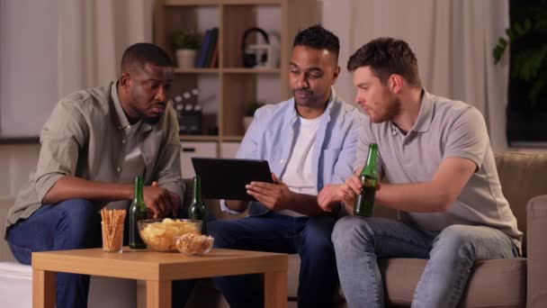 Mannelijke vrienden met tablet pc drinken bier thuis — Stockvideo