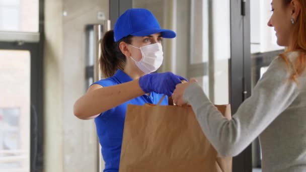 Entrega chica en máscara dando bolsa de papel a la mujer — Vídeo de stock