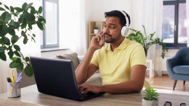 Homem em fones de ouvido com laptop trabalhando em casa — Vídeo de Stock