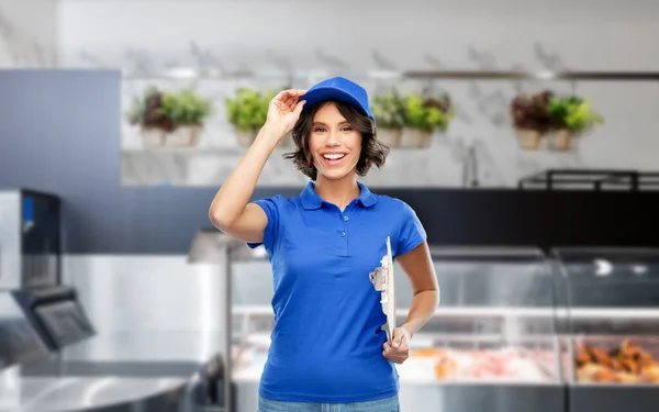 Happy smiling delivery girl with clipboard at shop — Stock Photo, Image