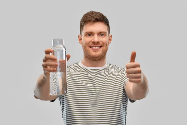 Щасливий усміхнений чоловік тримає воду в скляній пляшці — стокове фото