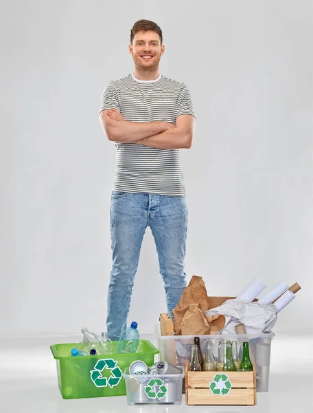 Lächelnder Mann beim Sortieren von Papier, Metall und Plastikmüll — Stockfoto