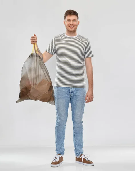 Улыбающийся мужчина держит мусорный мешок с бумажными отходами — стоковое фото