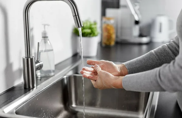 Mulher lavar as mãos com sabão líquido na cozinha — Fotografia de Stock