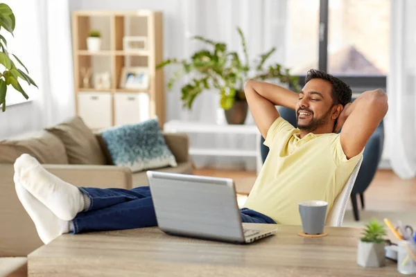Hombre con el ordenador portátil y los pies en la mesa en casa oficina — Foto de Stock