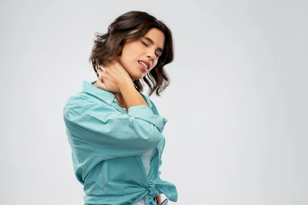 Молодая женщина в рубашке страдает от боли в шее — стоковое фото