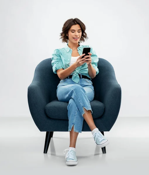 Ευτυχισμένη γυναίκα με smartphone κάθεται στην πολυθρόνα — Φωτογραφία Αρχείου