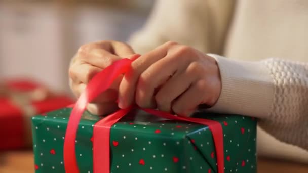Руки упаковки рождественский подарок и галстук лук — стоковое видео