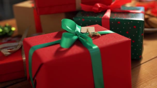 Kéz egymásra csomagolt karácsonyi ajándékok az asztalon — Stock videók