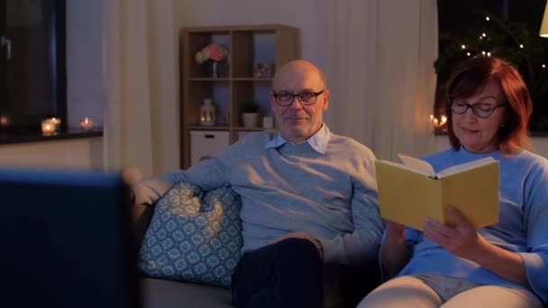 Anziani coppia guardando la tv e la lettura del libro a casa — Video Stock