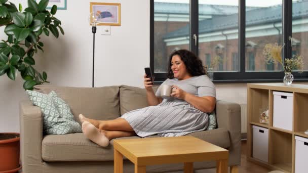 Mujer con teléfono inteligente beber café en casa — Vídeos de Stock