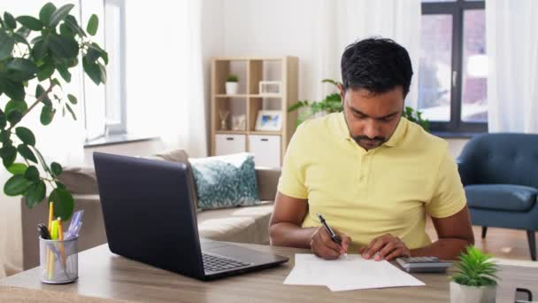 Homem com calculadora, laptop e papéis em casa — Vídeo de Stock