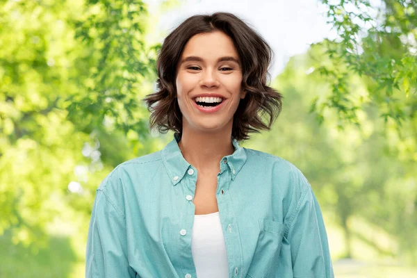 Lächelnde junge Frau über grünen natürlichen Hintergrund — Stockfoto