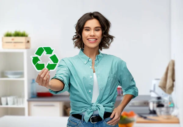 Улыбающаяся молодая женщина держит зеленый знак утилизации — стоковое фото