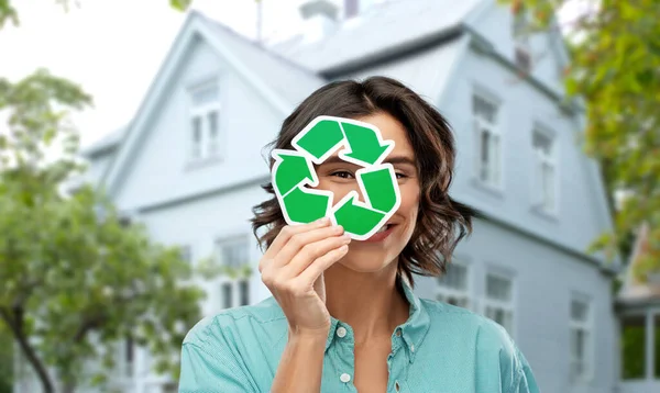 Mulher sorrindo olhando através do sinal de reciclagem verde — Fotografia de Stock