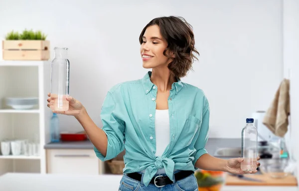 Usmívající se mladá žena srovnávající láhve vody — Stock fotografie
