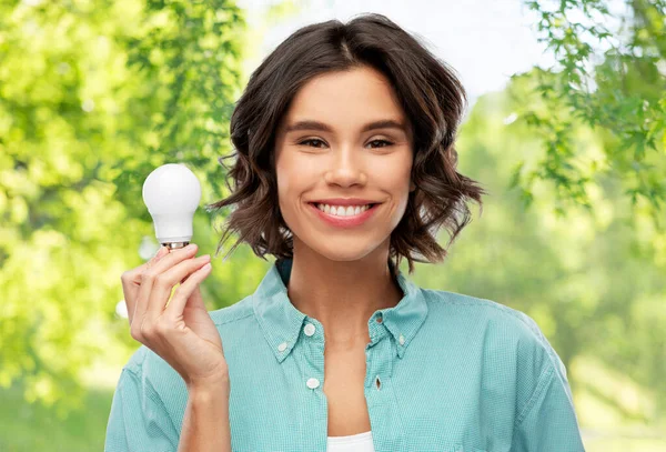 Sorrindo mulher segurando lâmpada de poupança de energia — Fotografia de Stock