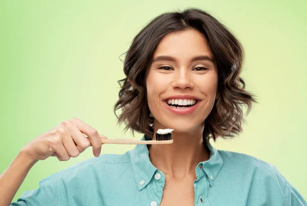 Lächelnde Frau mit Zahnpasta auf hölzerner Zahnbürste — Stockfoto