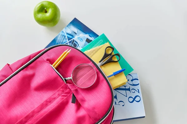 Mochila con libros, útiles escolares y manzana — Foto de Stock