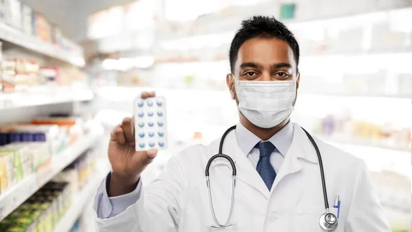 Indiai férfi orvos vagy gyógyszerész maszkban gyógyszerrel — Stock Fotó