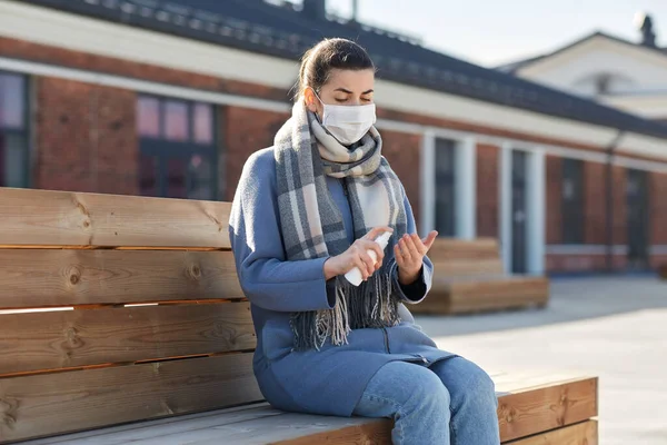 Vrouw in masker spuiten hand sanitizer buiten — Stockfoto