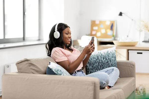 Kobieta ze smartfonem słuchająca muzyki w domu — Zdjęcie stockowe