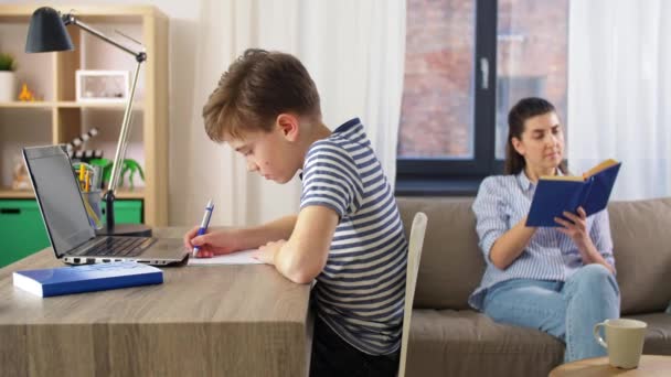 Студентський хлопчик з ноутбуком навчається онлайн вдома — стокове відео