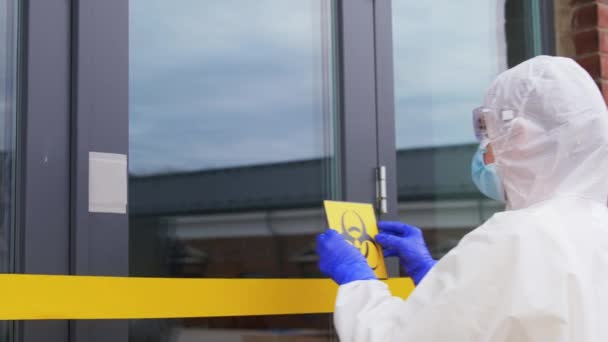 Trabajador de la salud pegando el signo de riesgo biológico a la puerta — Vídeos de Stock