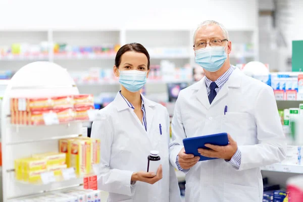 Boticários em máscaras com tablet pc na farmácia — Fotografia de Stock