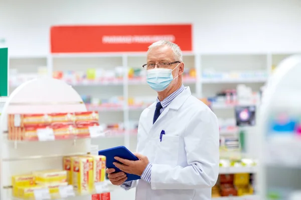 Vieil apothicaire masqué avec comprimé pc à la pharmacie — Photo