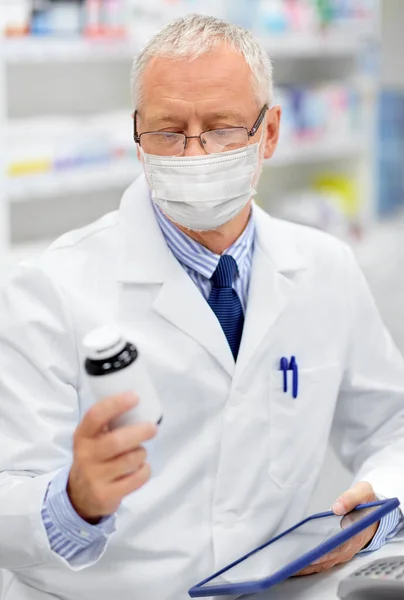 Vieil apothicaire masqué avec comprimé pc à la pharmacie — Photo