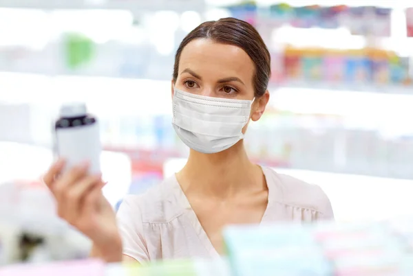 Female customer in mask with medicine at pharmacy — Stock Photo, Image